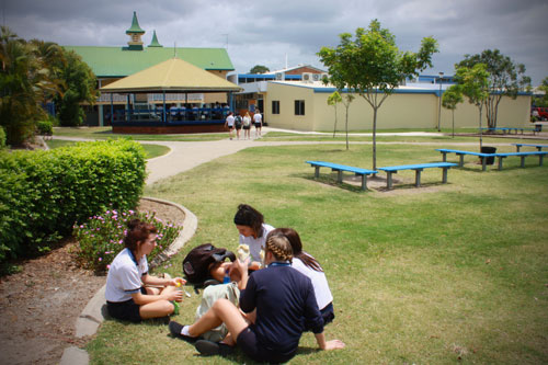 Female students sitting in a group on the grass in the school grounds.